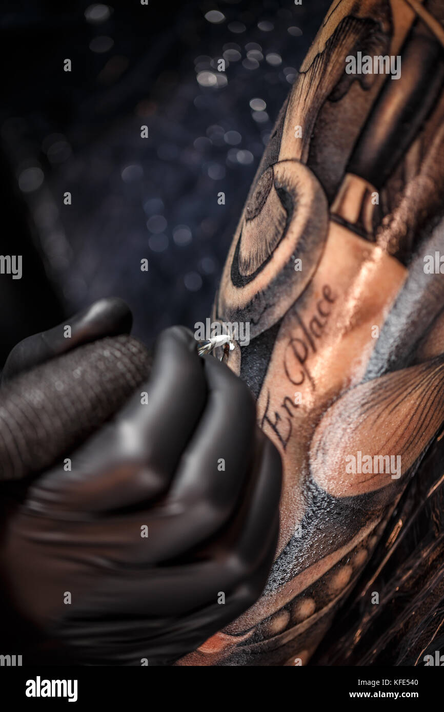 Le mani dell'artista tattoo tatuaggio di uomo di pelle Foto Stock