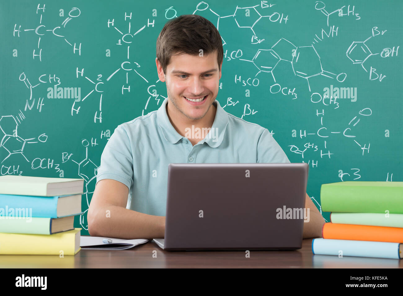 Giovane uomo felice utilizzando laptop mentre studiano in aula Foto Stock