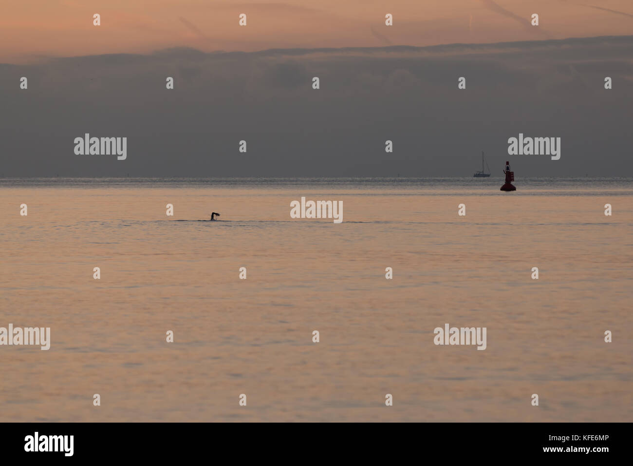 Il braccio di un nuotatore prendendo un inizio di mattina tuffo nel mare di Brighton. in background e vi è una boa e dietro di questa un yacht Foto Stock