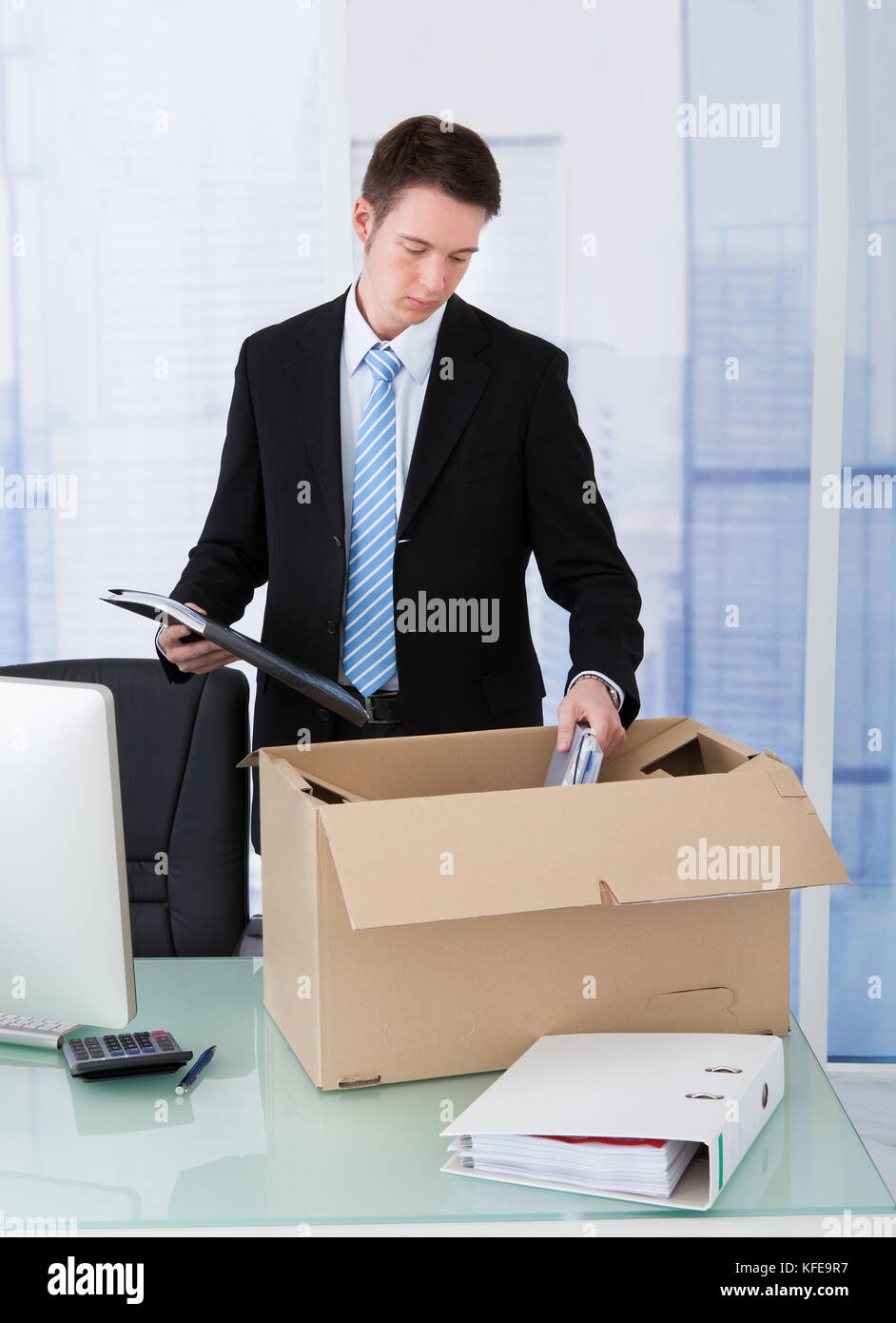 Giovane imprenditore la raccolta di forniture per uffici in scatola di cartone a scrivania da ufficio Foto Stock