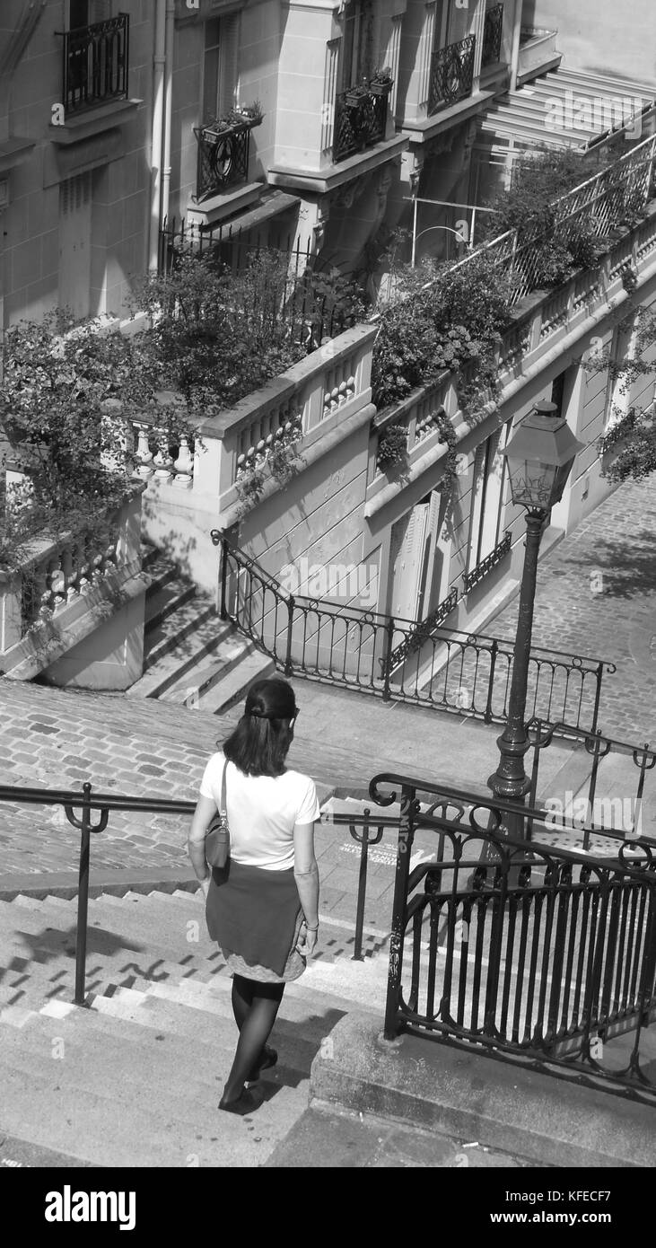Una giovane donna cammina verso il basso un tipico insieme di passi trovati in Montmartre a Parigi, girato in bianco e nero Foto Stock
