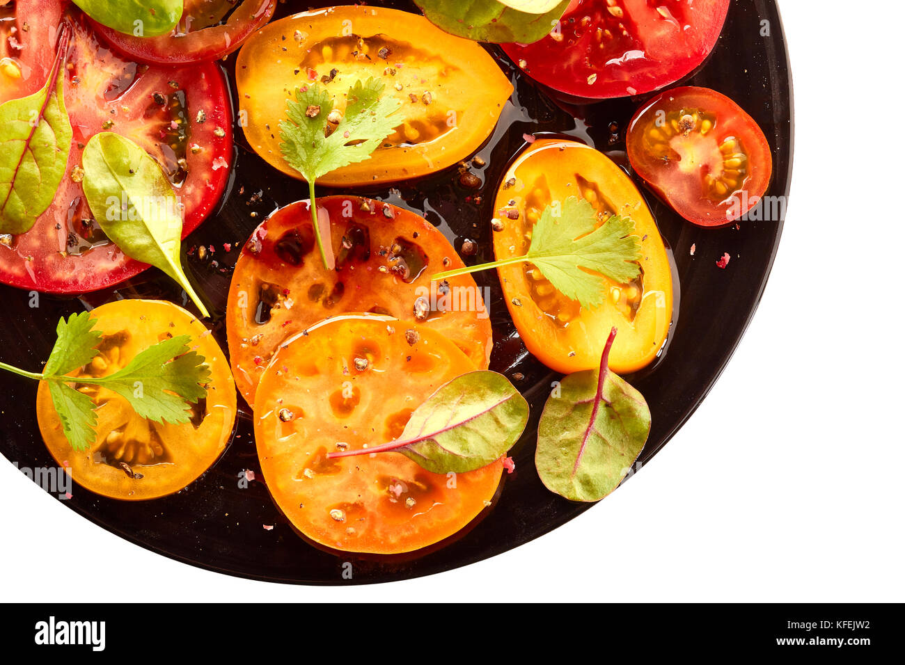 La piastra nera di insalata con pomodori a fette su bianco Foto Stock