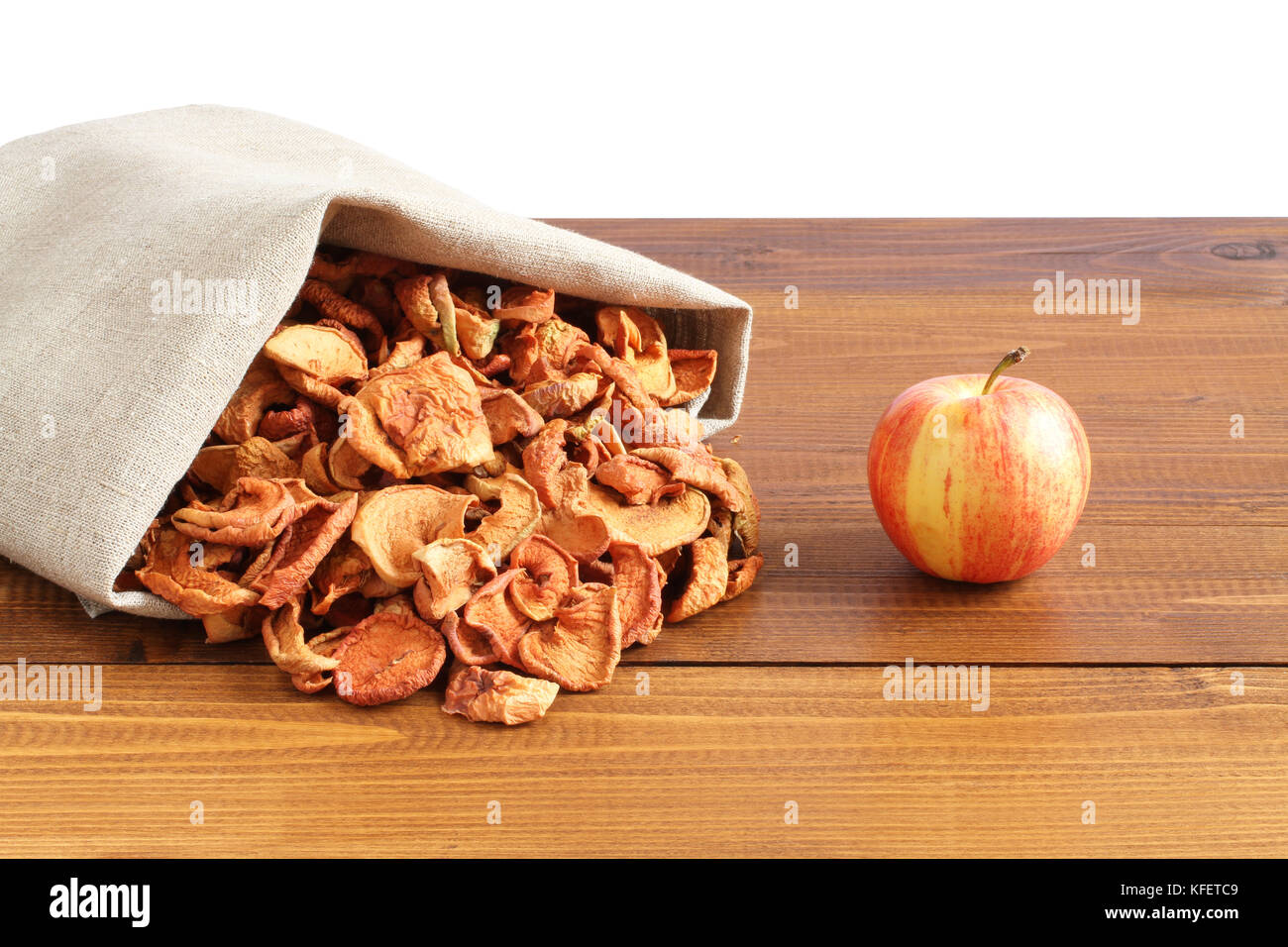 Pezzi essiccati di mele in ruvida tela di lino che giace su di un tavolo di legno Foto Stock