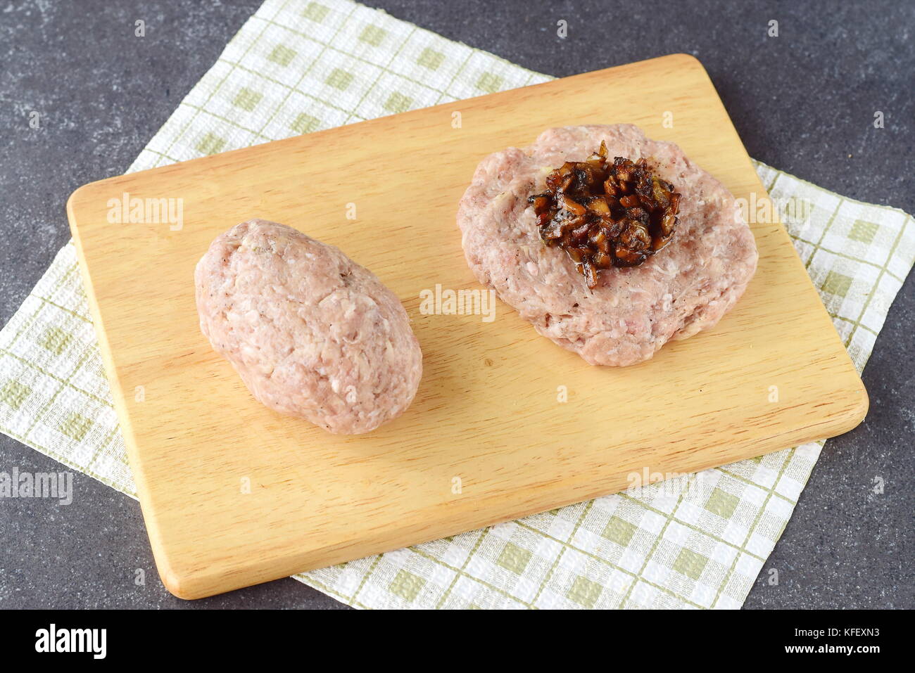Polpettine di carne con ripieno di funghi su un tagliere di legno. passo per passo per la cottura Foto Stock