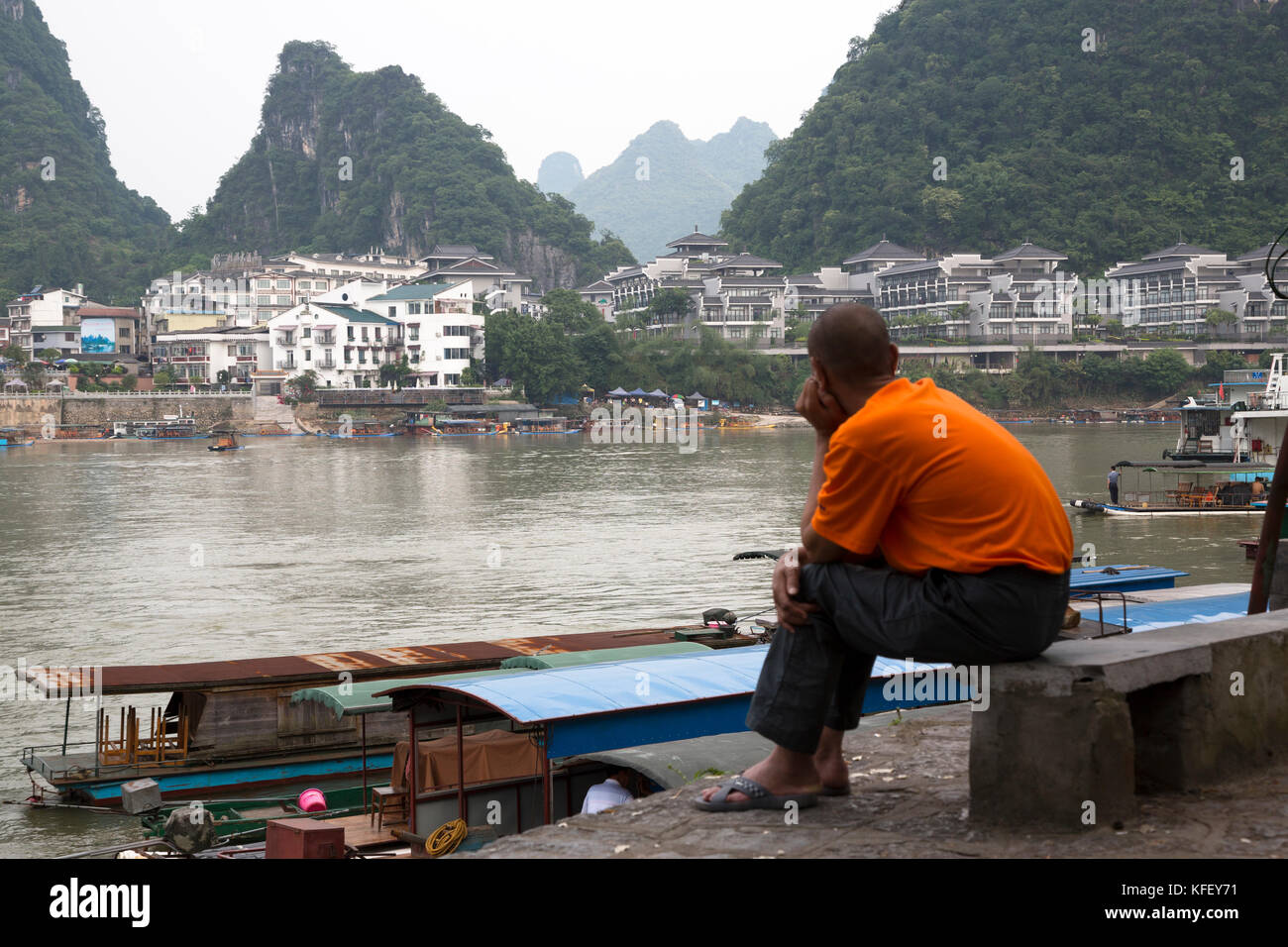 Uomo cinese guarda a Yangshuo centro città e il fiume Yulong in Guangxi Zhuang regione autonoma della Repubblica popolare cinese Foto Stock