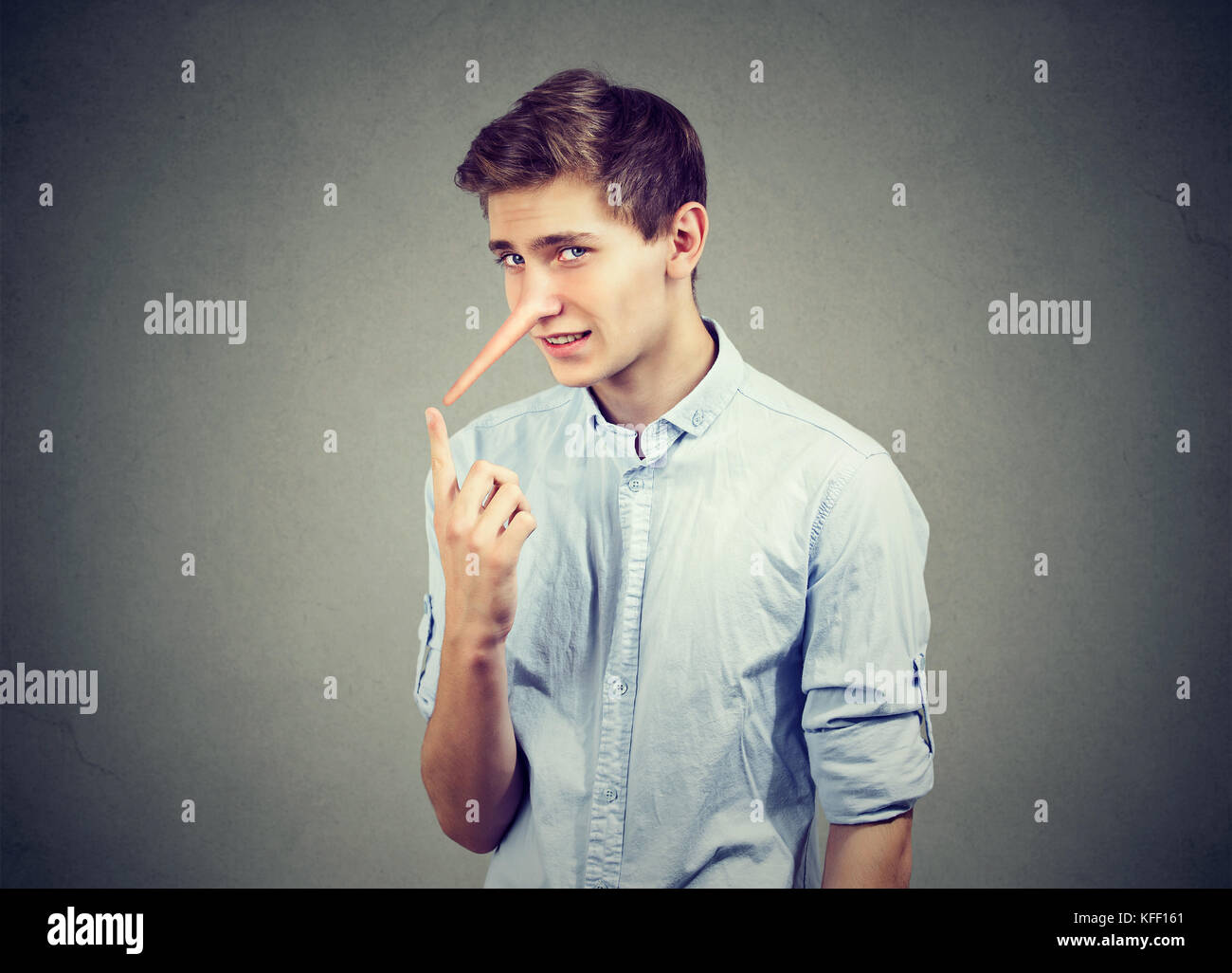 Uomo con il naso lungo isolato sul muro grigio Sfondo. bugiardo concetto. le emozioni umane, sentimenti. Foto Stock