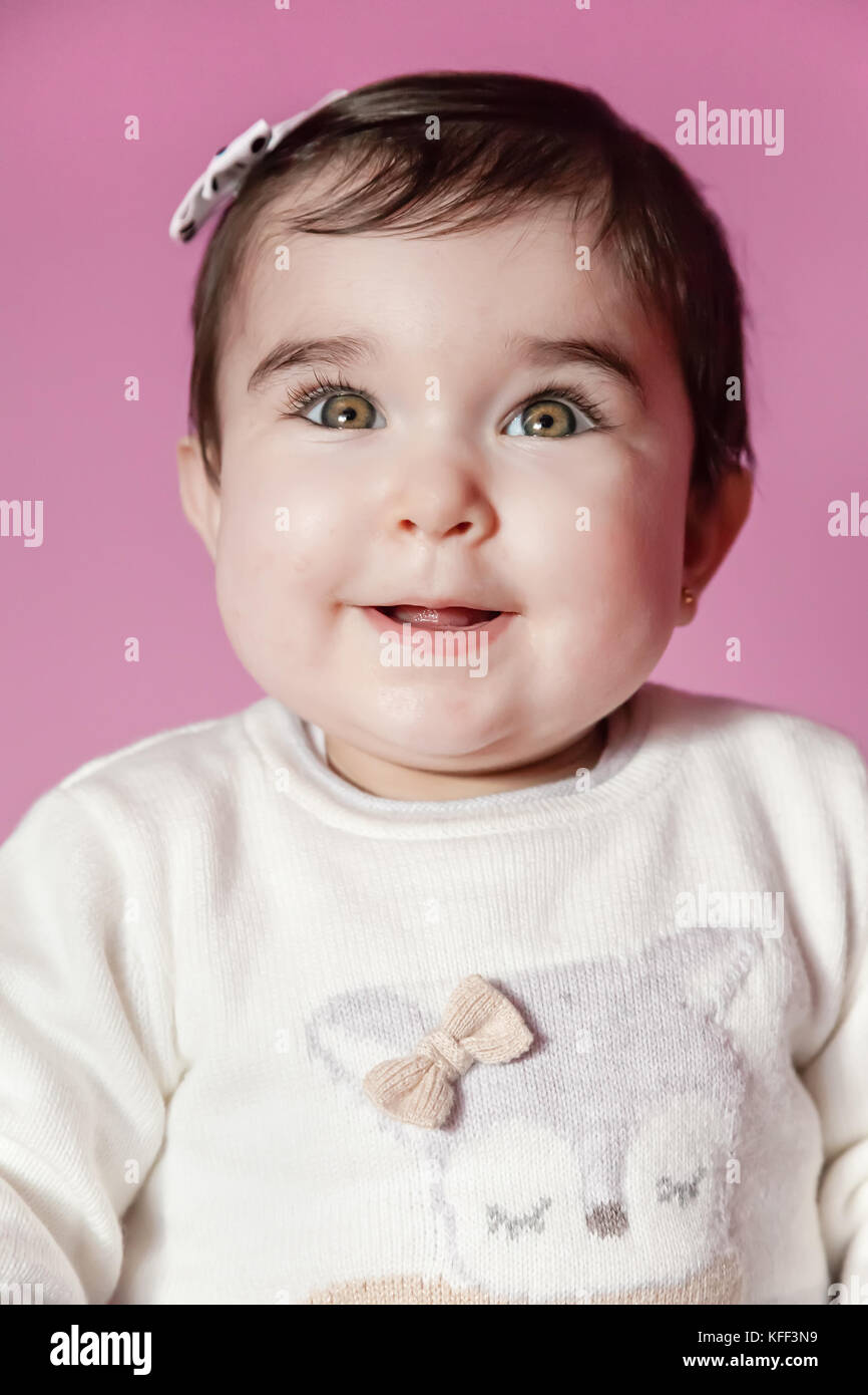 Carino, bello e happy baby ragazza sorridente ritratto indossando un fiocco nei capelli. nove mesi di età / baby ragazza sorridente sorriso felice carino pretty chubby divertito Foto Stock