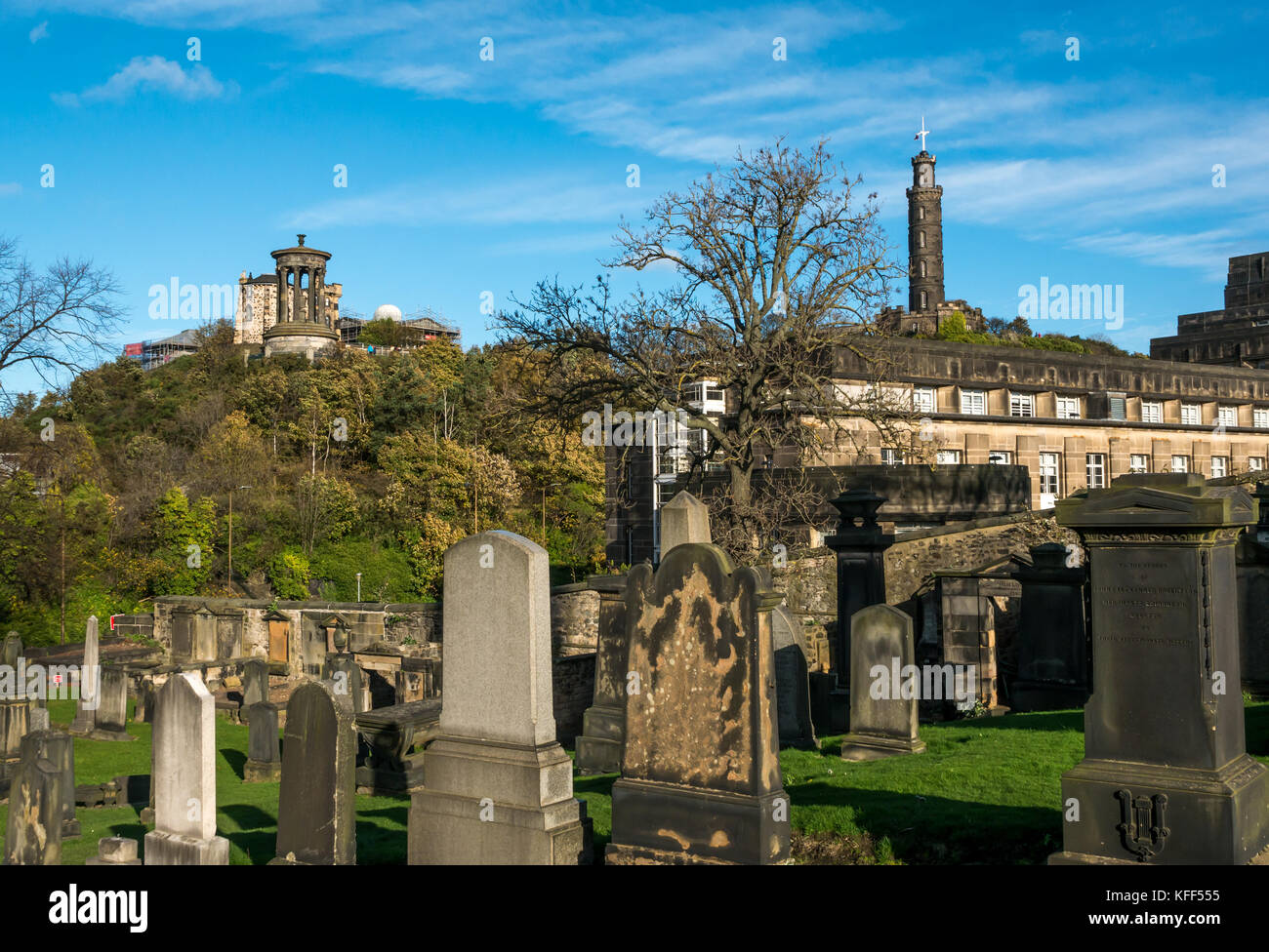 Vecchie lapidi in Old Calton seppellimento cimitero di massa Edimburgo in Scozia e la vista da Calton Hill, con colonna di Nelson e Dugald Stewart monumento Foto Stock
