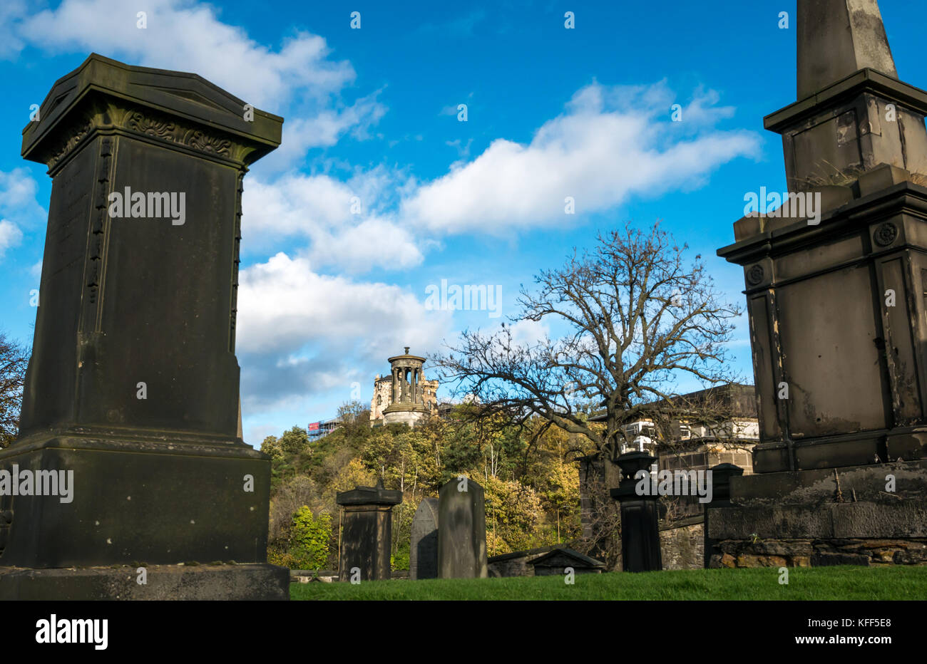 Le lapidi in Old Calton seppellimento cimitero di massa, Edimburgo, Scozia e vista di Calton Hill con il Dugald Stewart monumento Foto Stock