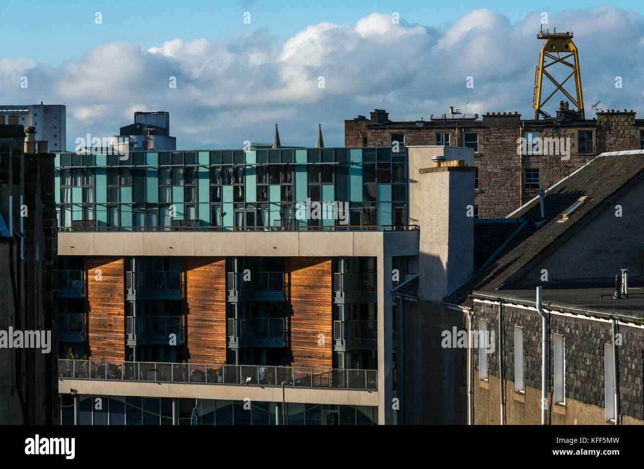 Vista sui tetti delle antiche e moderne costruzioni in Leith, Edimburgo, Scozia, con enormi giallo turbina eolica piattaforma in distanza Foto Stock