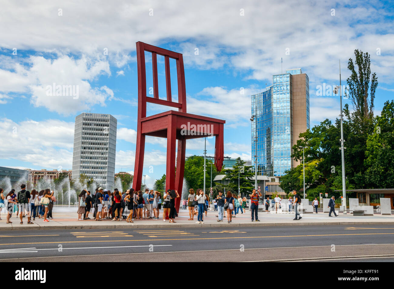 Nazioni Unite piazza con turisti alla sedia rotta e l'Organizzazione mondiale della proprietà intellettuale in sede. Ginevra, Svizzera. Foto Stock