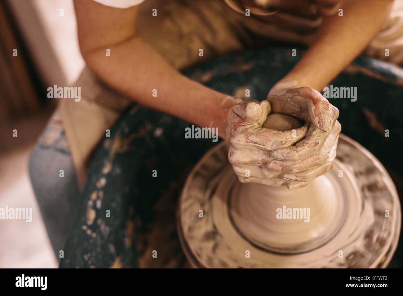 Potter facendo una pentola di creta sulla ruota di ceramiche in officina. Craftswoman creta con le mani sul volante in ceramica. Foto Stock