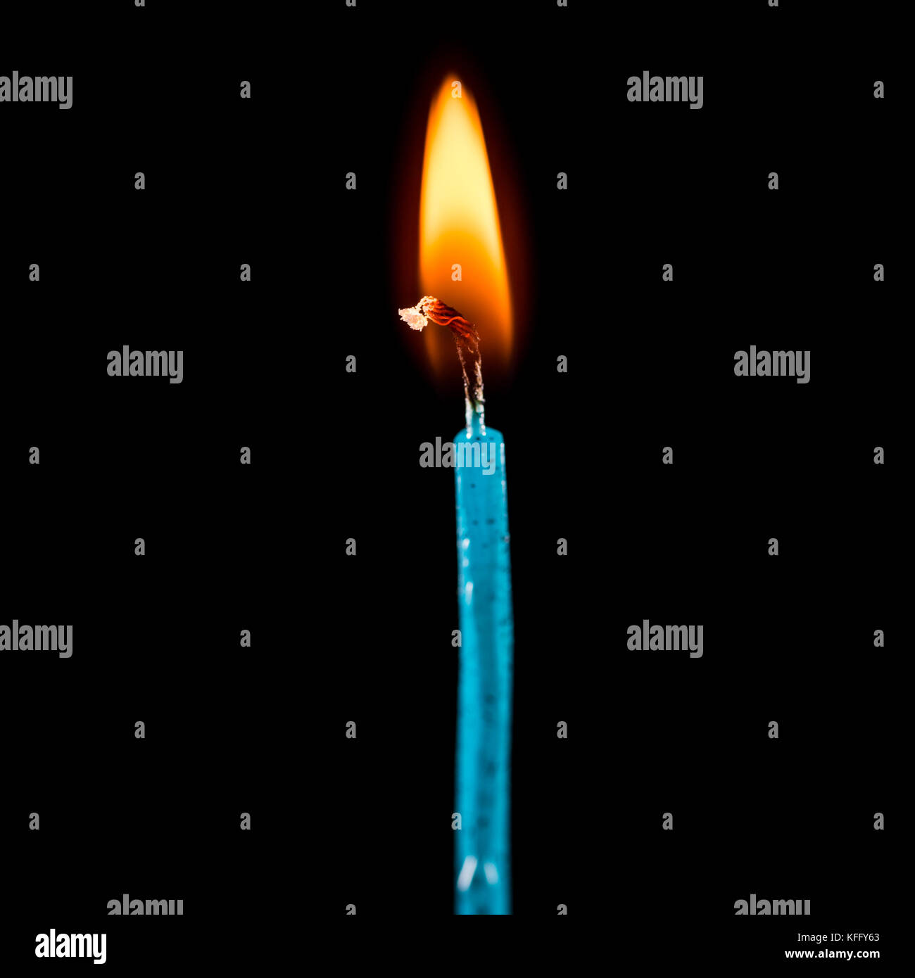 Una ripresa macro di un unico colore blu candela, bruciando contro uno sfondo nero. Foto Stock