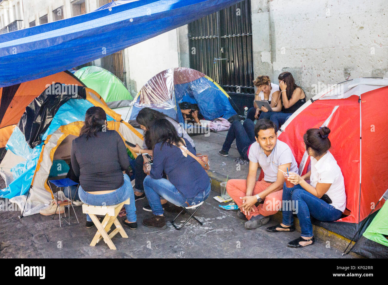 Un gruppo di giovani insegnanti rilassarsi vicino alle loro tende a pelo sul lato strada dopo lo sfratto da Oaxaca zocalo occupato per anni da vari gruppi di protesta Foto Stock