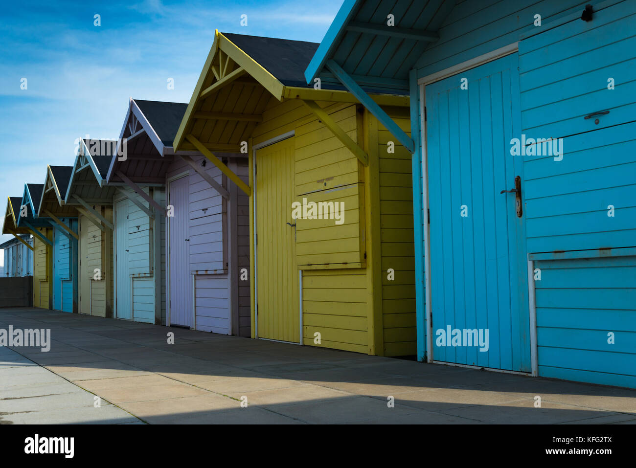 Una fila di sfuggente di identiche cabine in legno in autunno la luce del sole pomeridiano sul lungomare in Lancashire città portuale di Fleetwood, England, Regno Unito Foto Stock