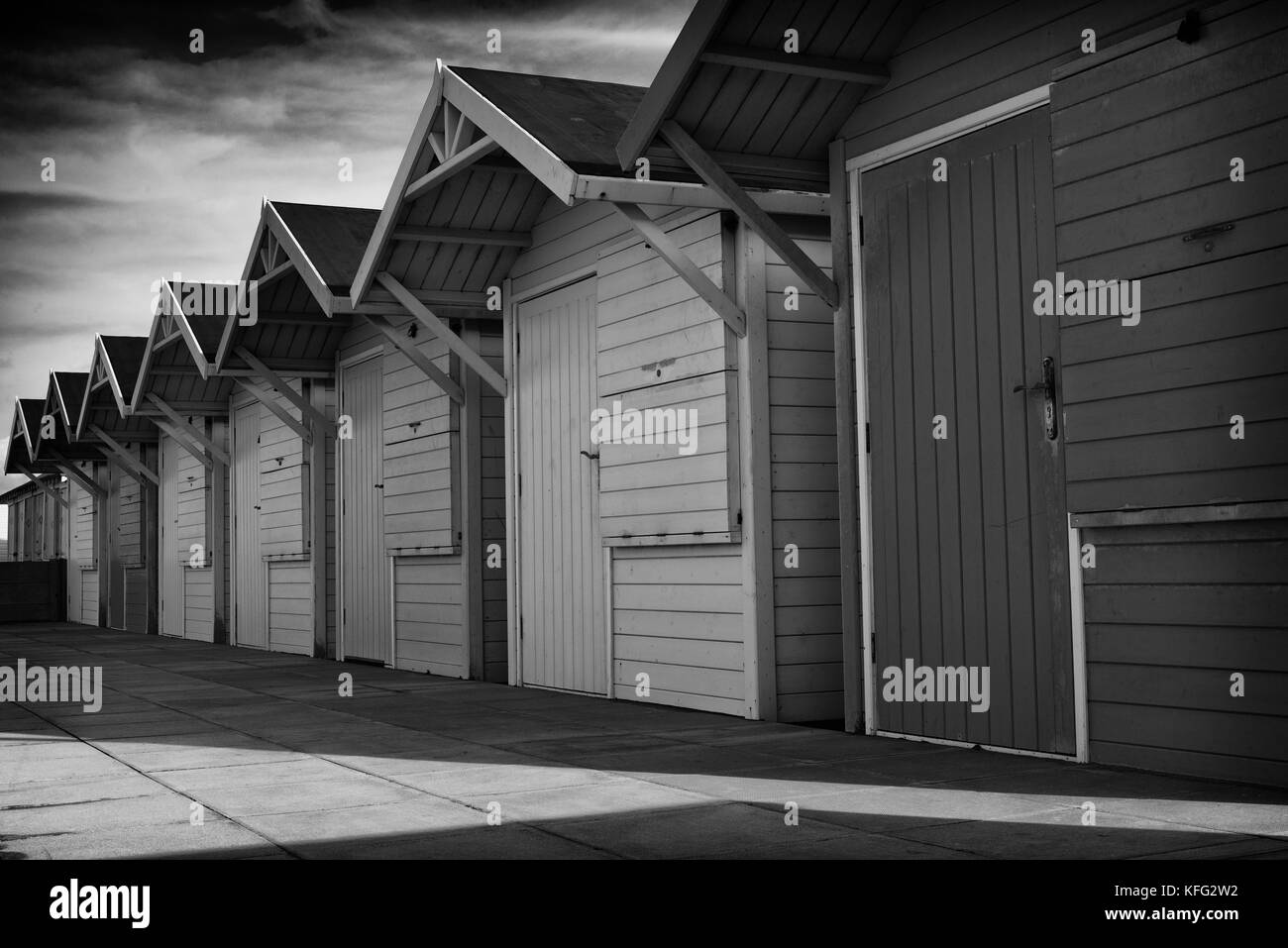 Una fila di sfuggente di identiche cabine in legno in autunno la luce del sole pomeridiano sul lungomare in Lancashire città portuale di Fleetwood, England, Regno Unito Foto Stock