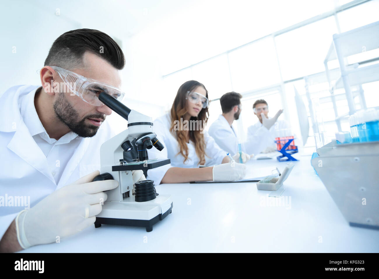 Maschio qualificato tecnico di laboratorio guardando i campioni al microscopio Foto Stock