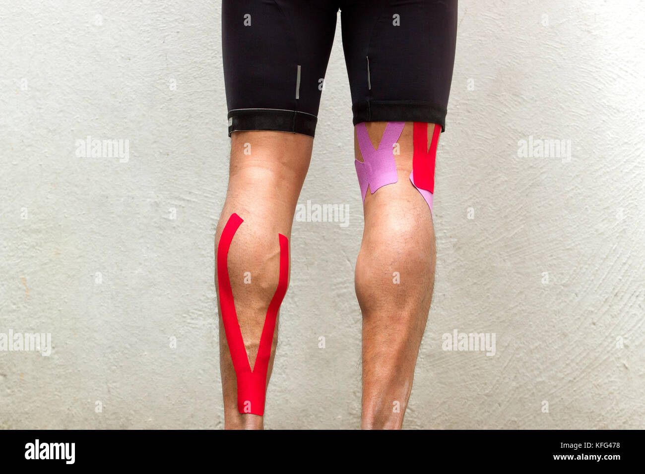 La foto in orizzontale di un ciclista maschio con kinesio nastro sul suo posteriori della coscia e del polpaccio muscolo per ridurre il dolore Foto Stock