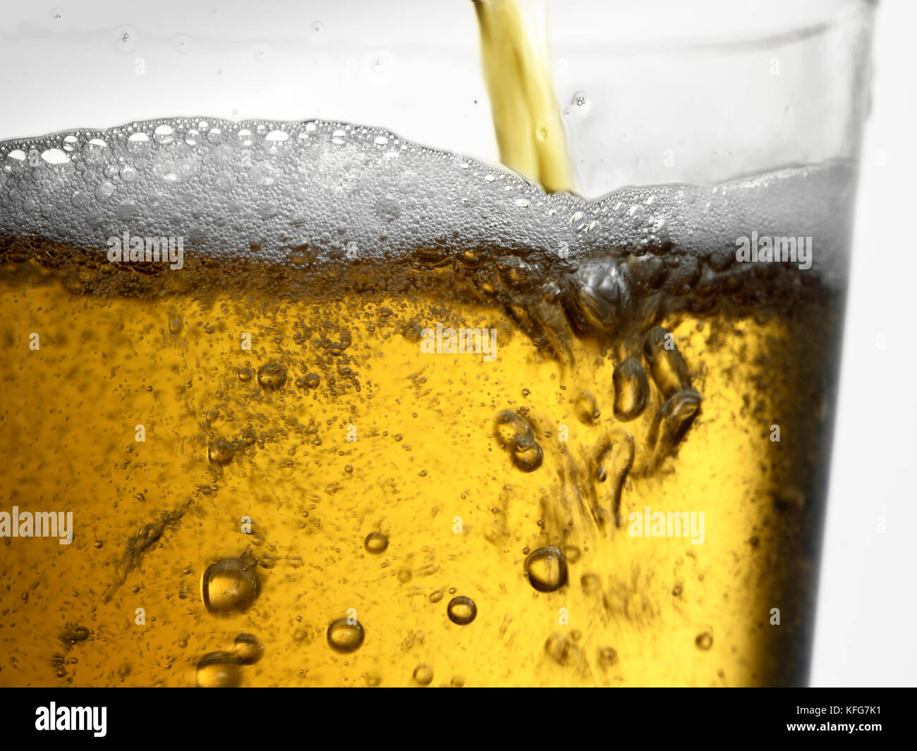 Primo piano azione girato di ambra oro per spillare la birra in vetro trasparente con bolle e di schiuma di testa Foto Stock