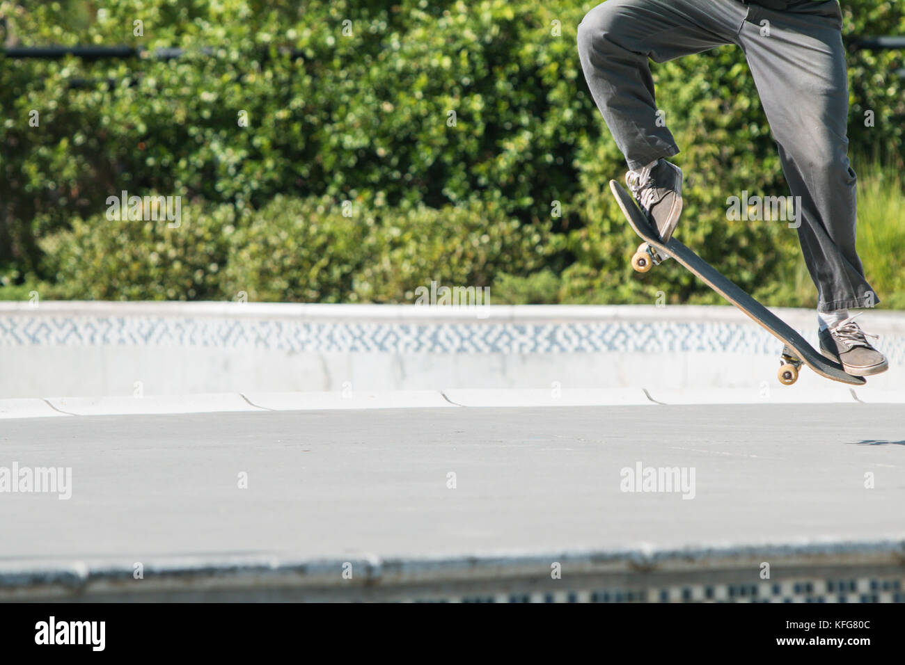 Un guidatore di skateboard utilizza le sue gambe e piedi per eseguire un trick skateboard in un parco di skateboard. Foto Stock