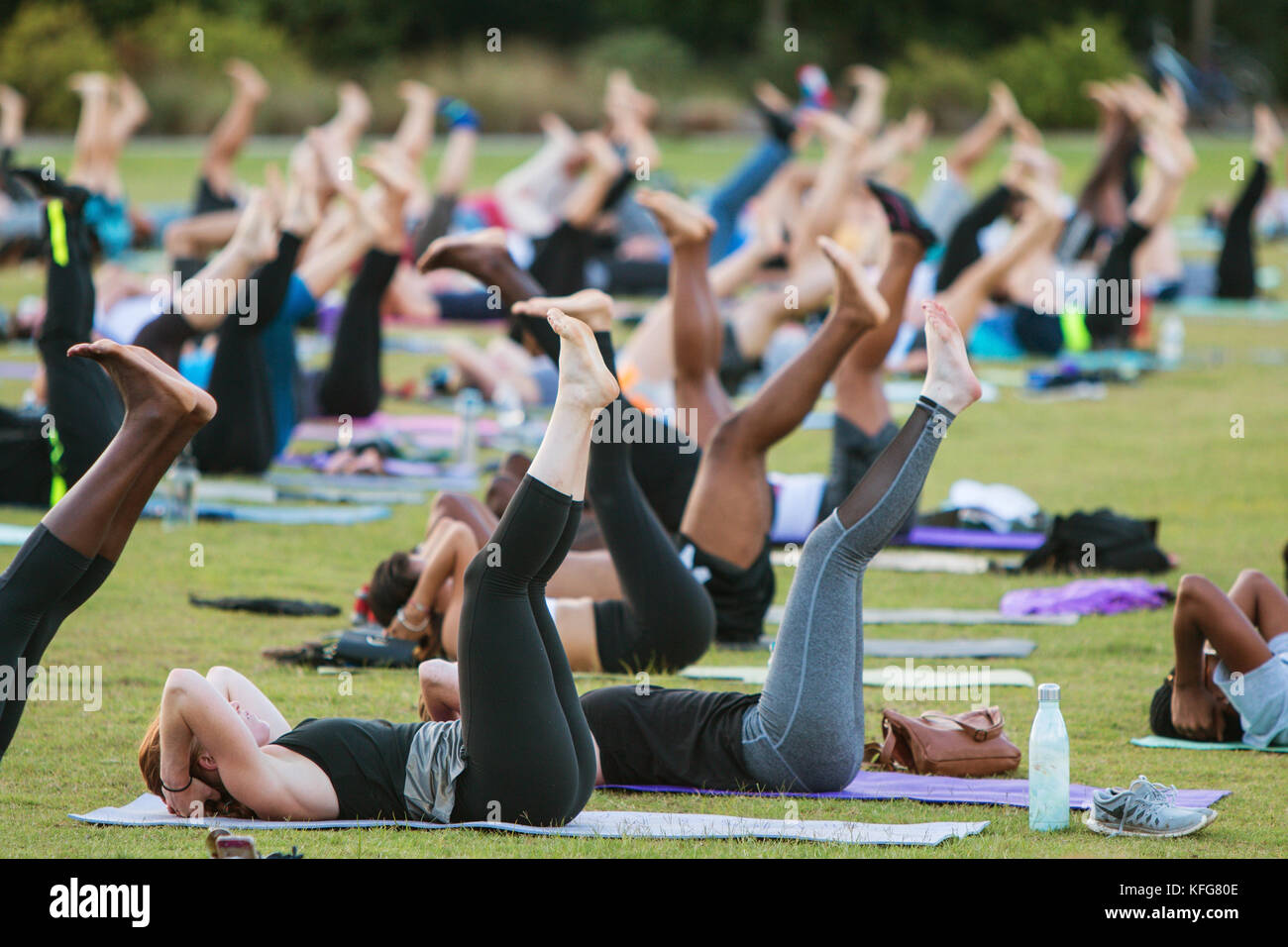 Atlanta, GA, Stati Uniti - 2 luglio 2017: Decine di persone fanno una posa yoga sdraiate sulla schiena mentre prendono parte a una lezione di yoga di gruppo gratuita. Foto Stock
