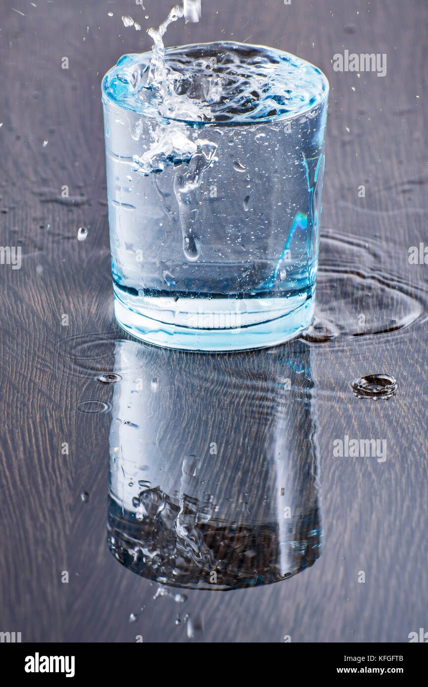 Un riempimento di vetro di acqua in una chiave di alta fotografia con un bianco sfondo luminoso Foto Stock