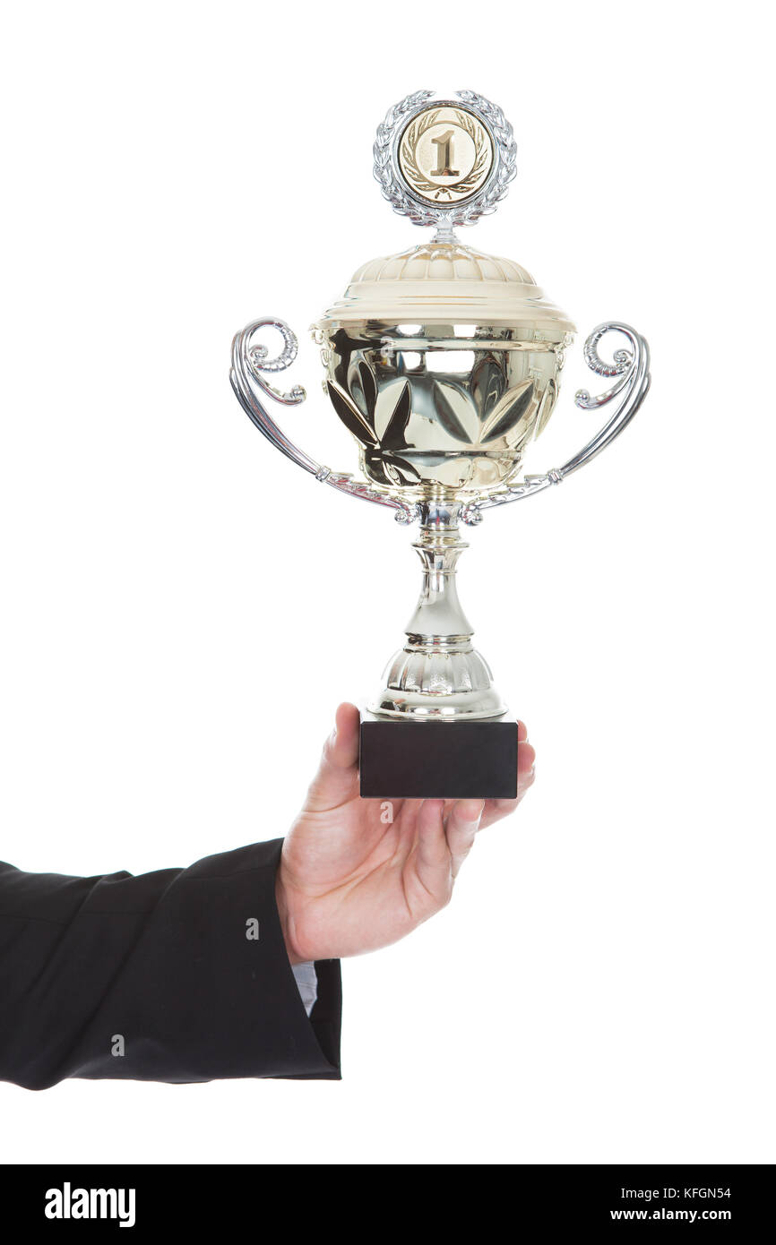 La mano di un uomo d affari con visualizzazione di un grande trofeo Silver Cup come una ricompensa per il suo successo e il raggiungimento isolato su bianco Foto Stock