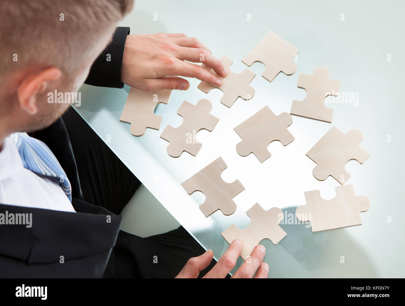 Imprenditore con un puzzle sparsi sulla sua scrivania cercando di far corrispondere i pezzi in un concetto di problem solving e incontro sfide aziendali ov Foto Stock