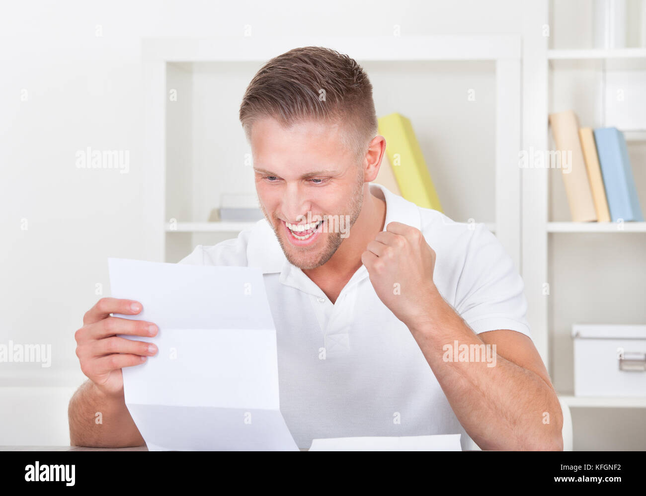 L'uomo tifo in giubilo come egli legge una lettera la punzonatura il pugno in aria come egli legge la buona novella Foto Stock