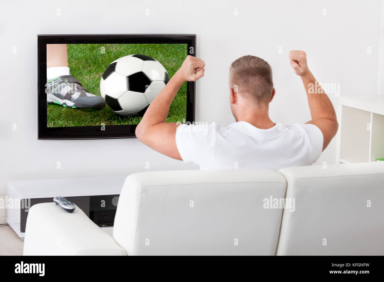 Emozionato tifoso di calcio a guardare una partita in televisione in  possesso di un pallone da
