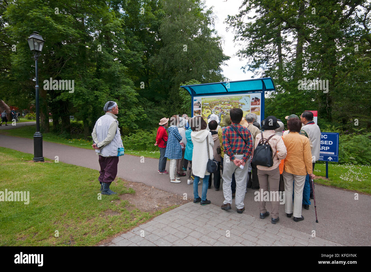 Gruppo di turisti vicino al segno di informazioni di Muckross House e giardini, Parco Nazionale di Killarney, nella contea di Kerry, Irlanda Foto Stock