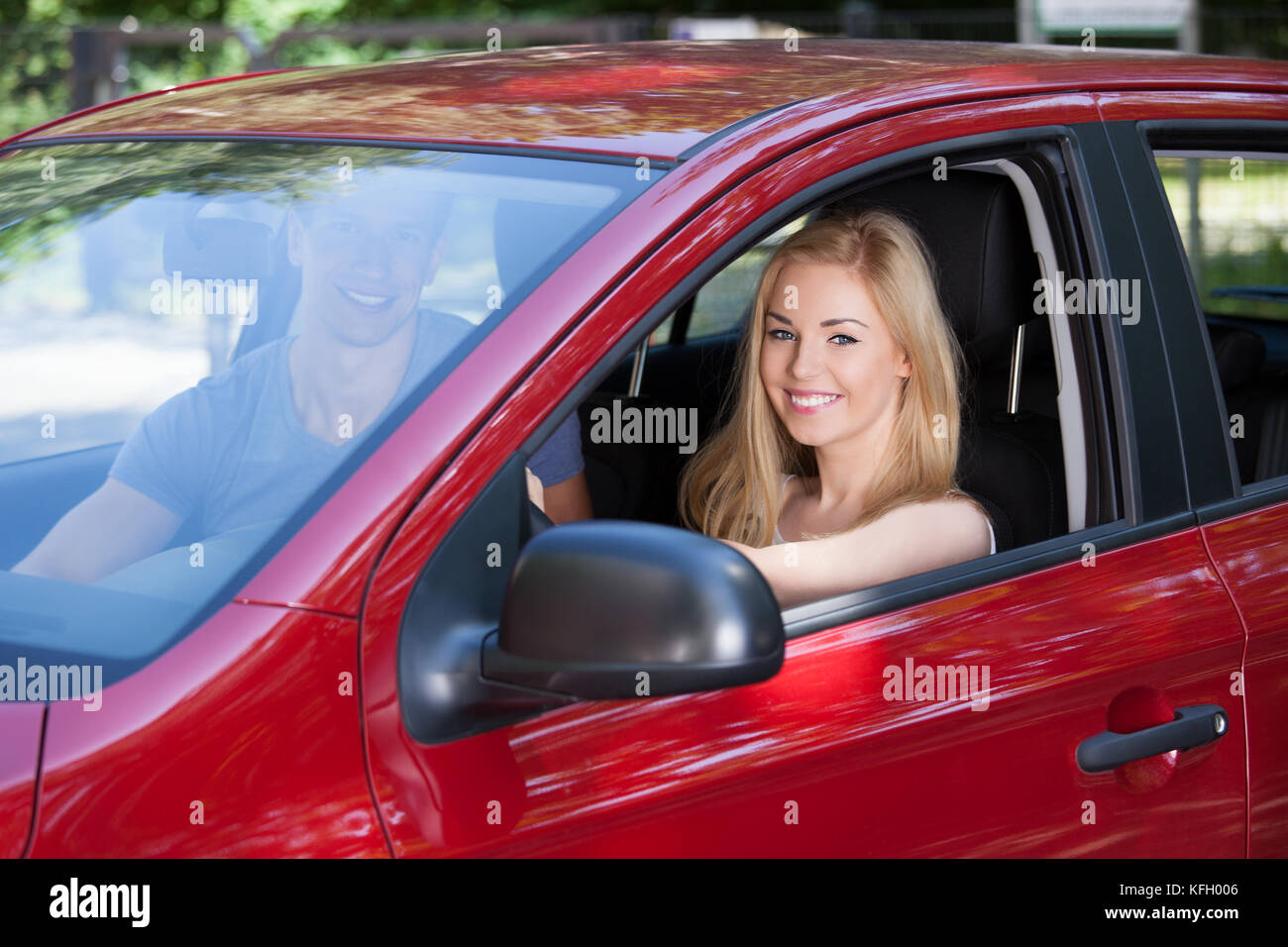 Ritratto di felice giovane donna con uomo seduto in auto nuova Foto Stock