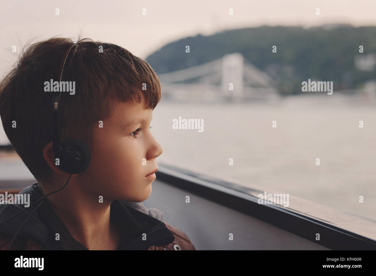Piccolo Ragazzo caucasico con ascolto in cuffia tour audio guidato sul Danubio, budapest, Ungheria Foto Stock