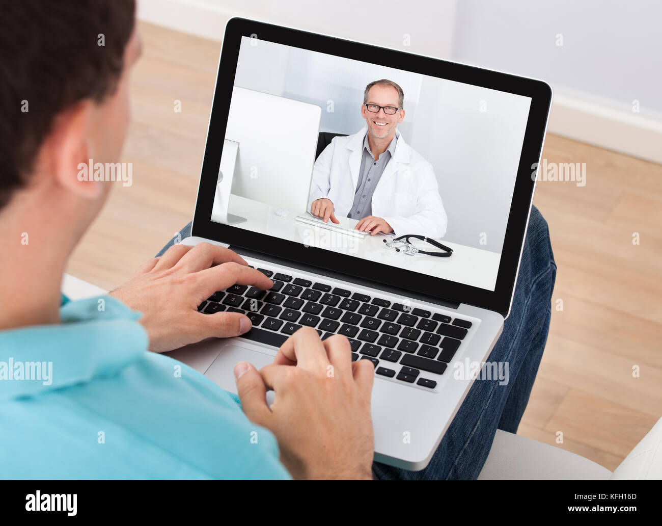 L'uomo avente la video chat con medico sul portatile a casa Foto Stock
