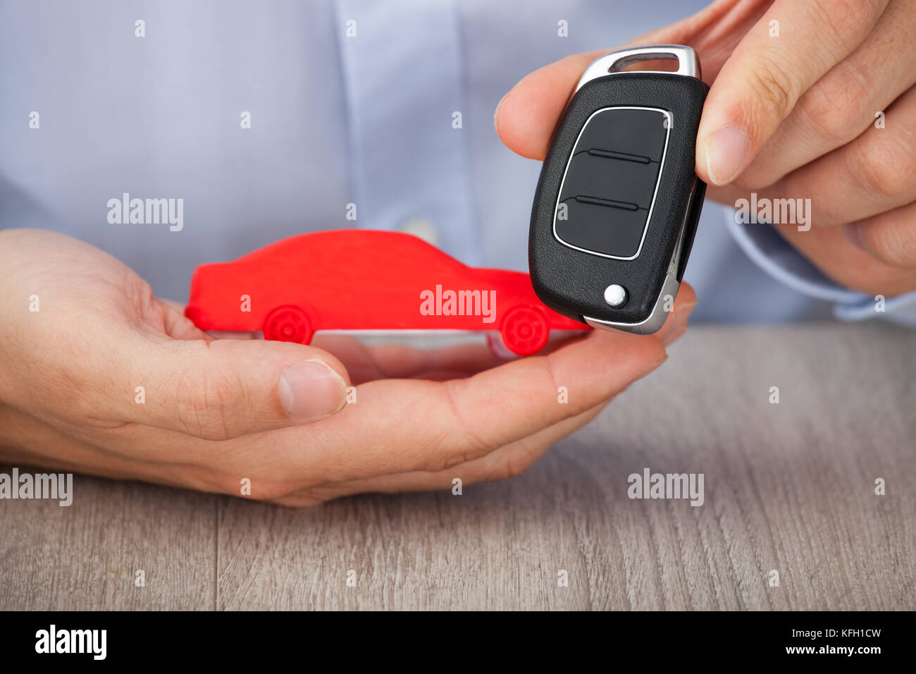 Sezione mediana di imprenditore con chiavi e rosso modello di auto alla reception Foto Stock