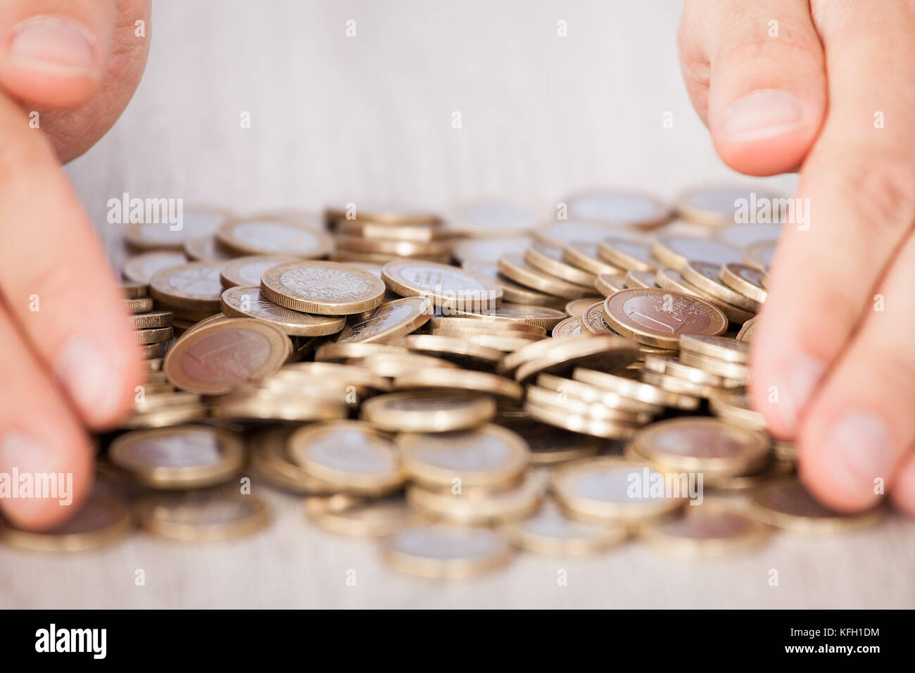 Primo piano di imprenditore con le mani in mano la raccolta di monete metalliche in euro alla scrivania in ufficio Foto Stock