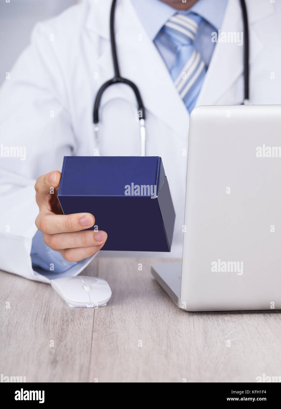 Sezione mediana del medico di medicina di contenimento box mentre utilizzando laptop in clinica Foto Stock