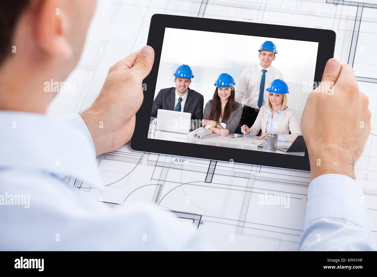 Immagine ritagliata di architetto maschio videoconferenze con il team attraverso la tavoletta digitale in ufficio Foto Stock