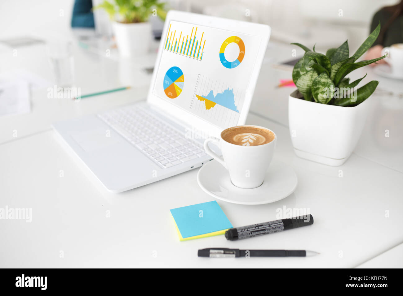 Laptop bianco in ufficio con le statistiche della società e la tazza di caffè Foto Stock