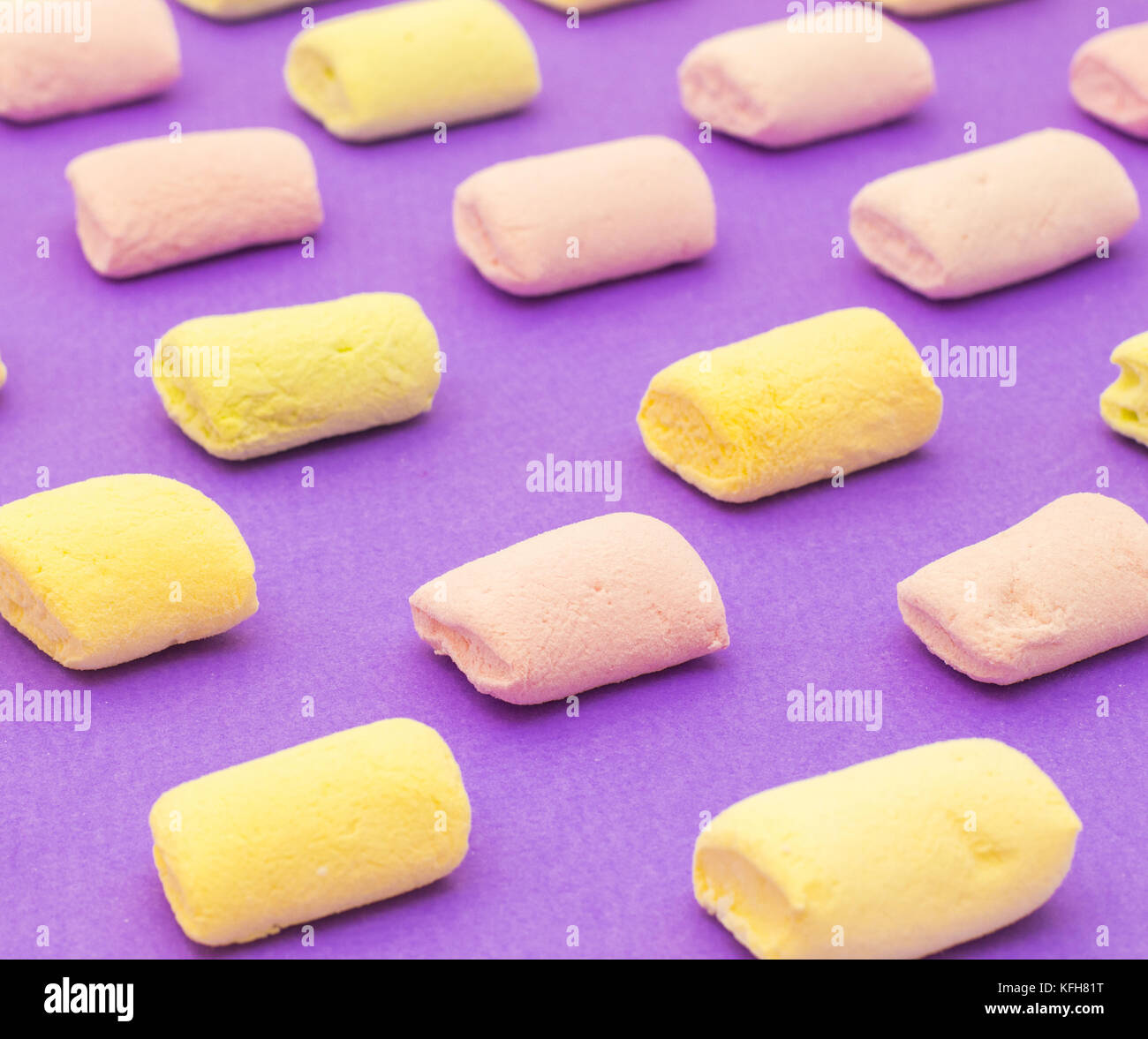 Modello con giallo e viola yummy marshmallows su sfondo viola Foto Stock