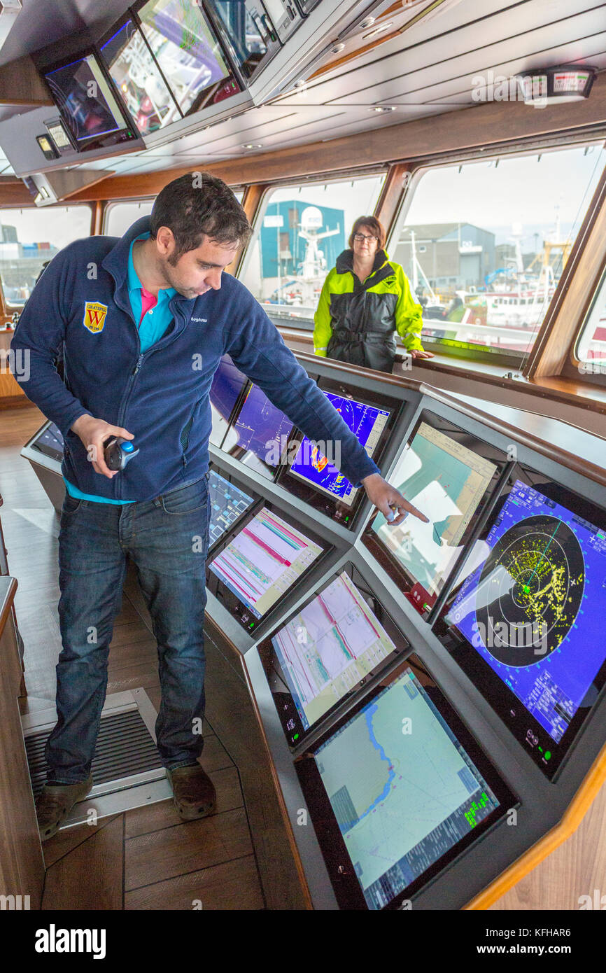 Lo skipper che spiega la nuova tecnologia sul ponte del nuovo peschereccio con reti da traino pelagiche 'grata' in Fraserburgh Harbour, Aberdeenshire, Scotland, Regno Unito Foto Stock