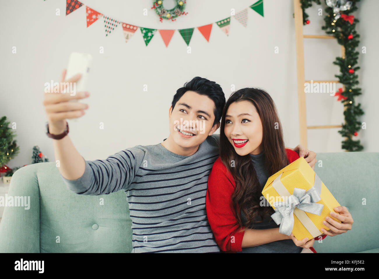 Natale coppia asiatica. Un uomo bello dando la sua fidanzata/moglie un regalo a casa per celebrare il nuovo anno persone Foto Stock