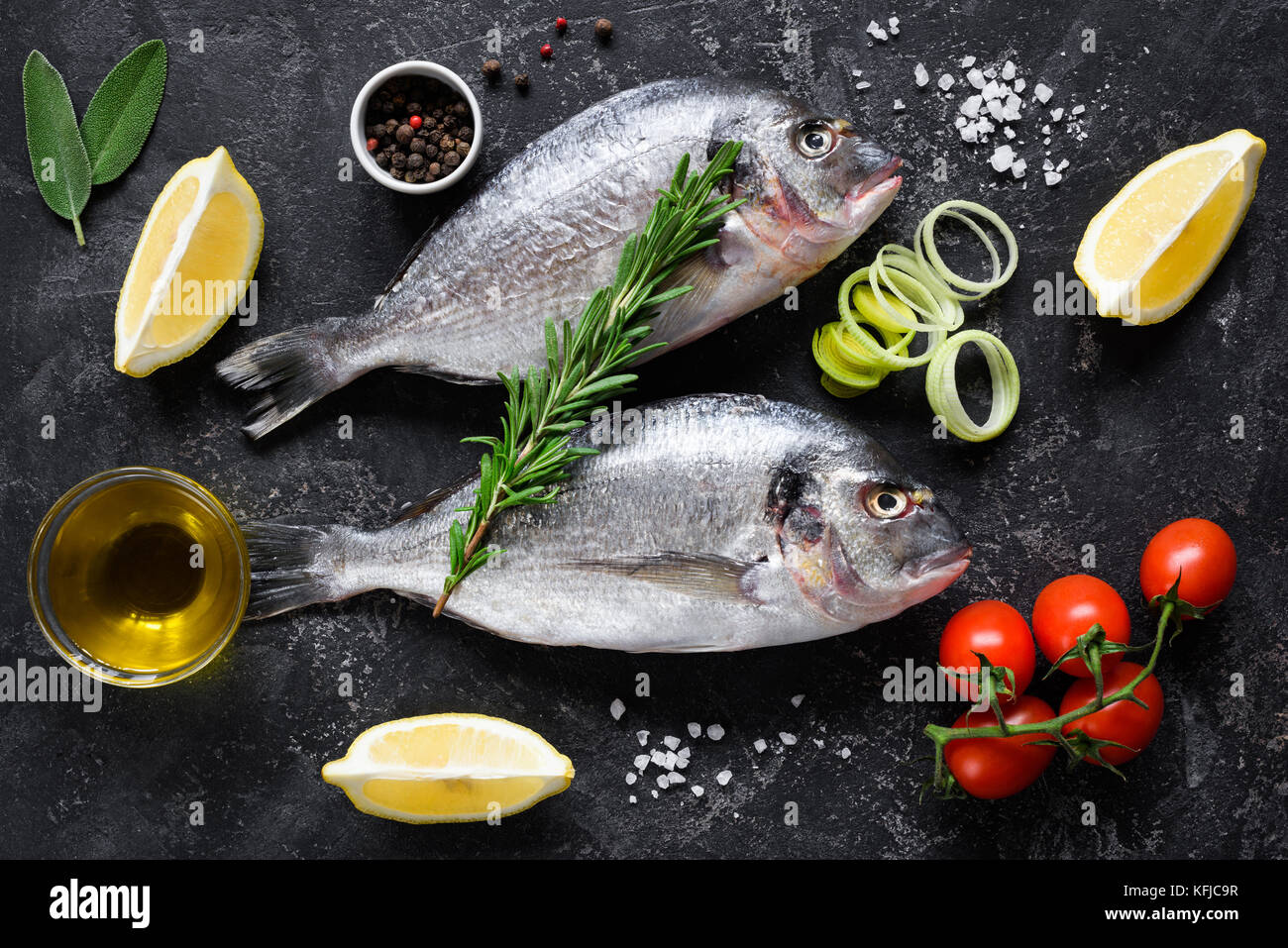 Non cotte fresche dorado o Orate di mare il pesce con le fette di limone e di spezie, erbe e verdure. Cucina mediterranea. Vista superiore Foto Stock