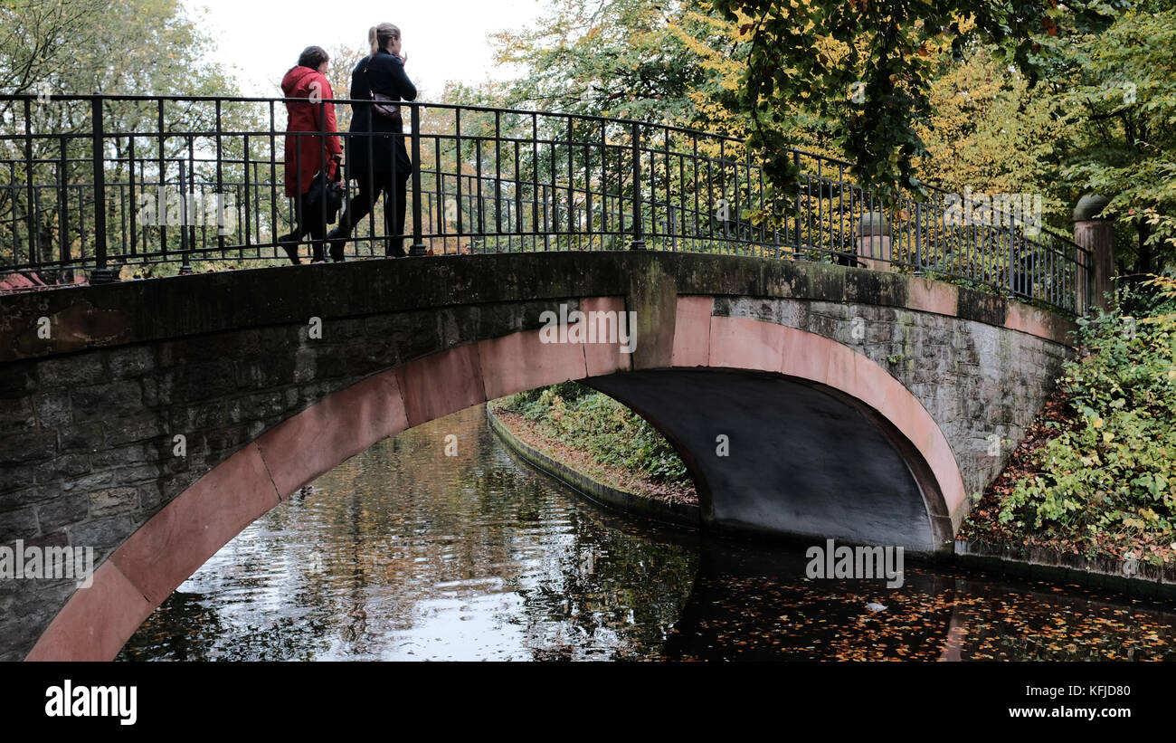 Due escursionisti attraversa un ponte godendo di colori autunnali nei giardini di Frederiksberg, Danimarca Foto Stock