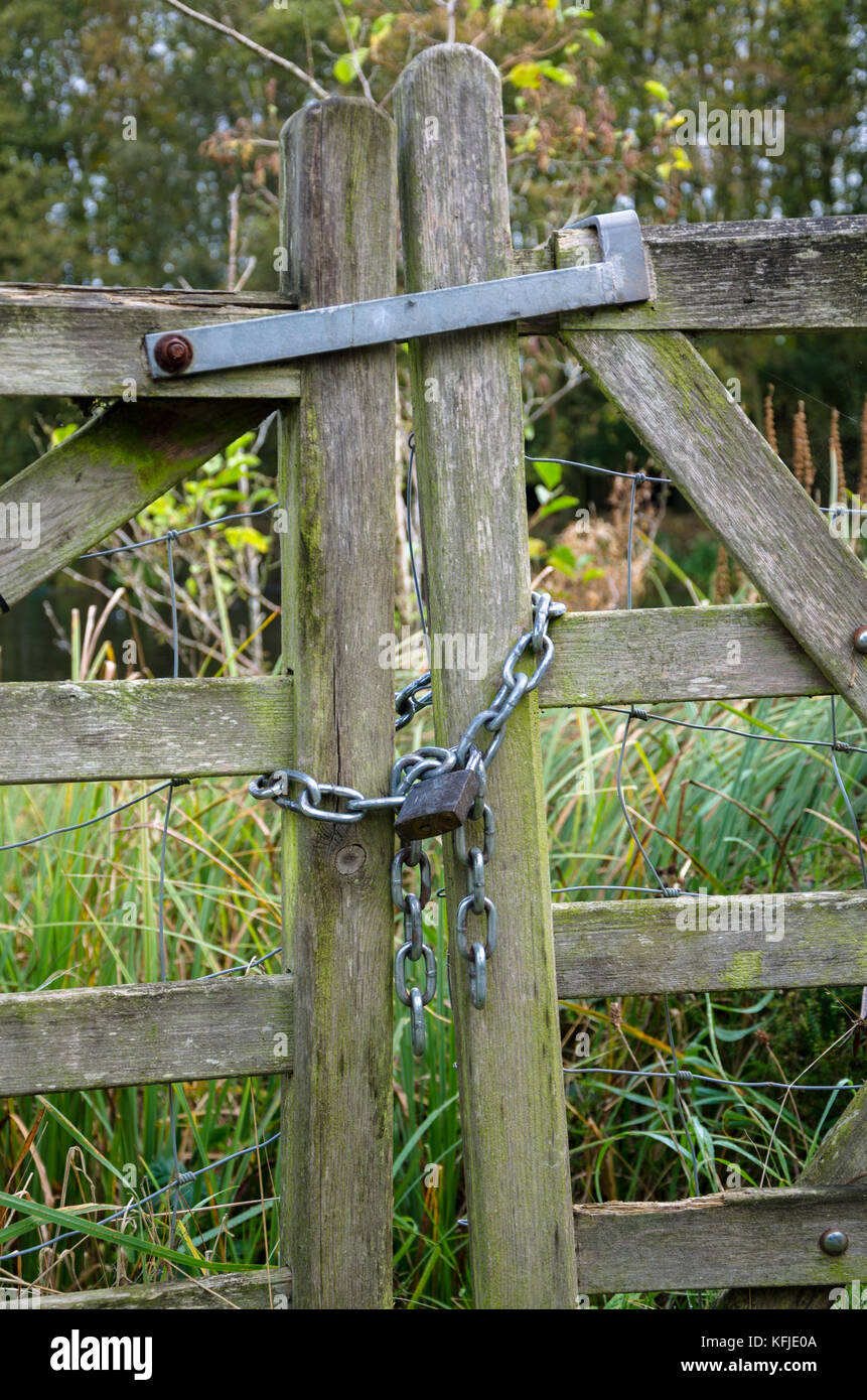 Un cancello in legno bloccato con una catena di metallo e un lucchetto. Foto Stock