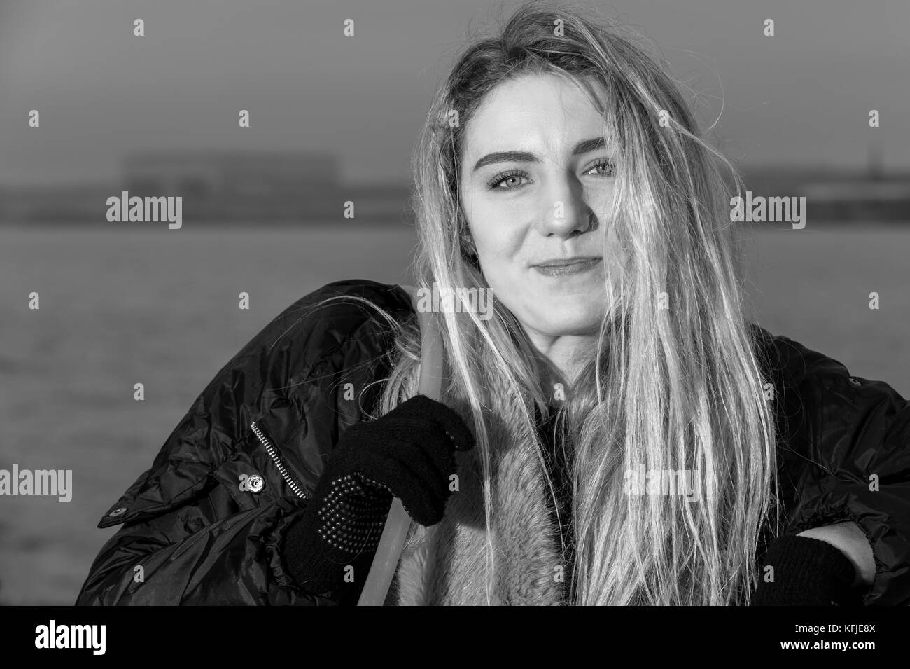 Ritratto di una ragazza guardando la telecamera, appoggiata contro il lungomare di ringhiere, in bianco e nero. Foto Stock