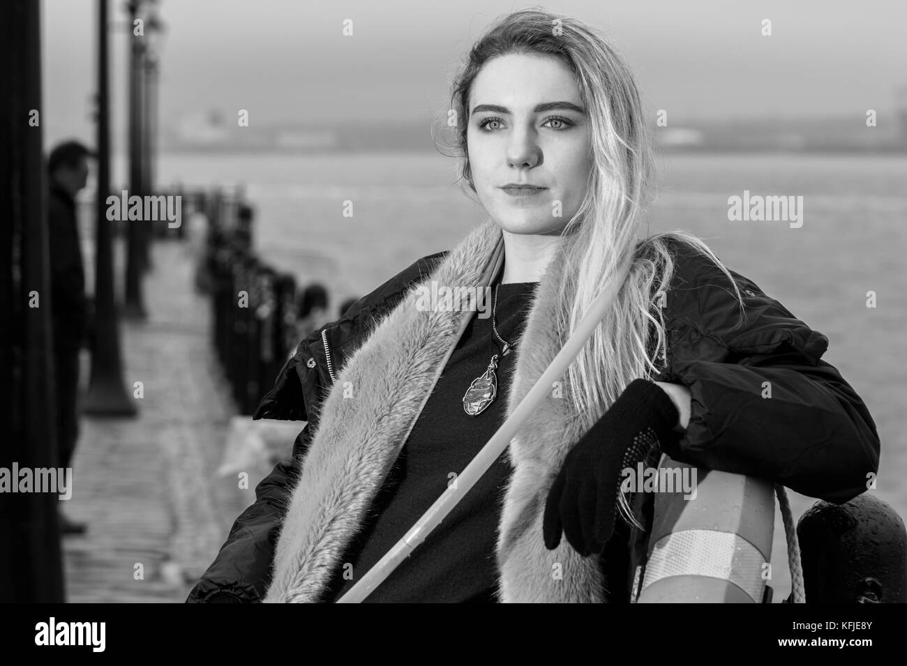 Ritratto di ragazza cerca passato fotocamera, appoggiata contro la promenade ringhiere, in bianco e nero. Foto Stock