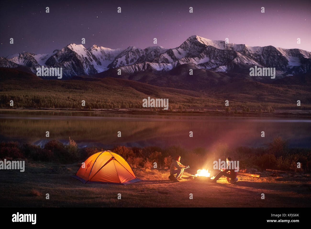 Due uomini turisti seduto alla tenda illuminata vicino al fuoco Foto Stock