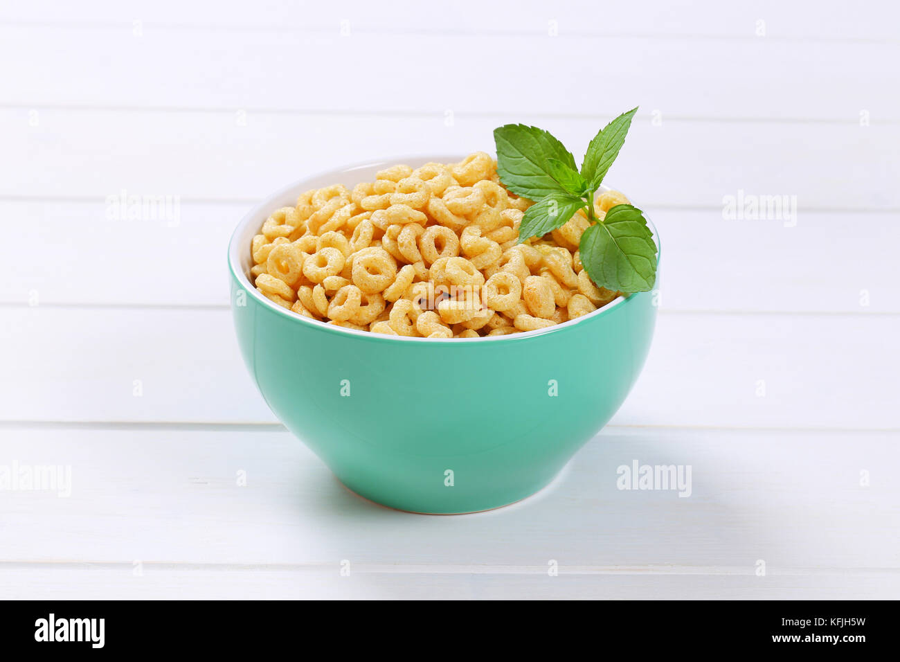 Ciotola di miele anelli di cereali in bianco sullo sfondo di legno Foto Stock