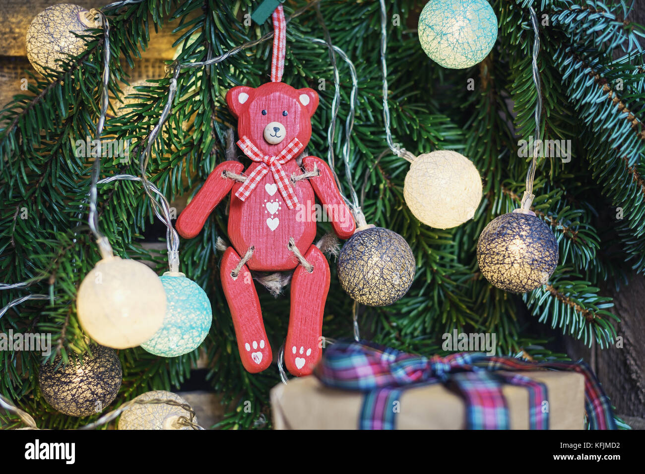 Rosso orso di legno appeso nel ramo di Natale decorato con illuminato palle di Natale Foto Stock